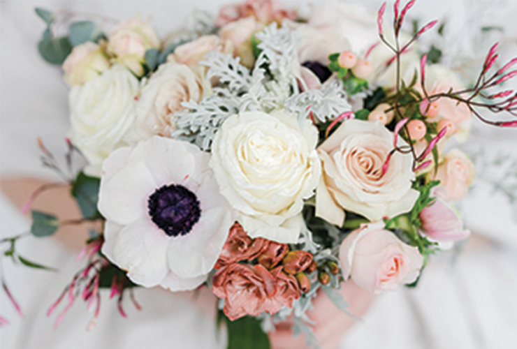 A bouquet of mostly white flowers with accents of muted pink roses. 