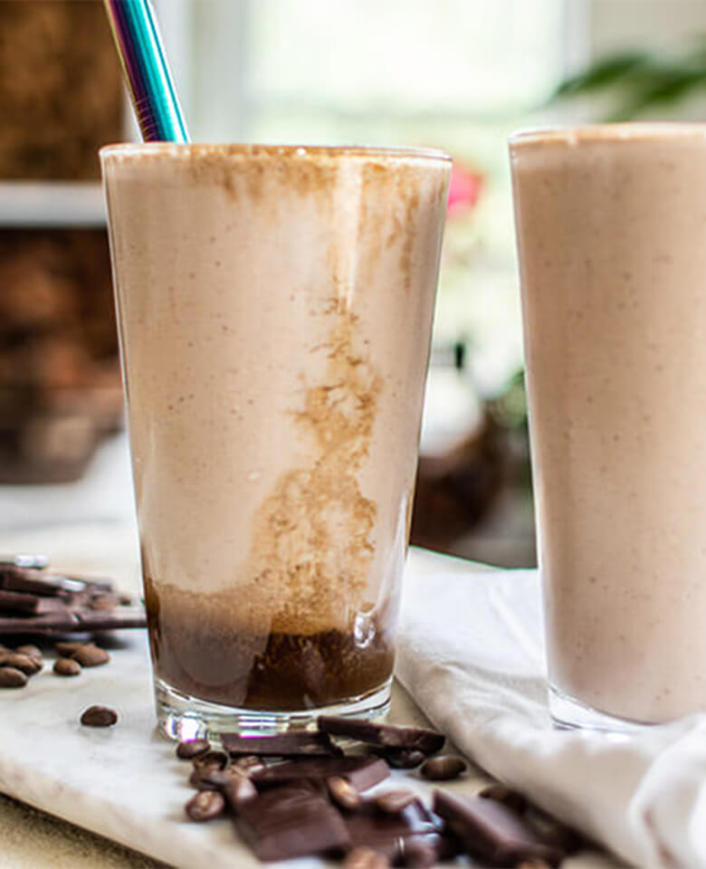 A chocolate superpower smoothie on a counter with a reusable straw