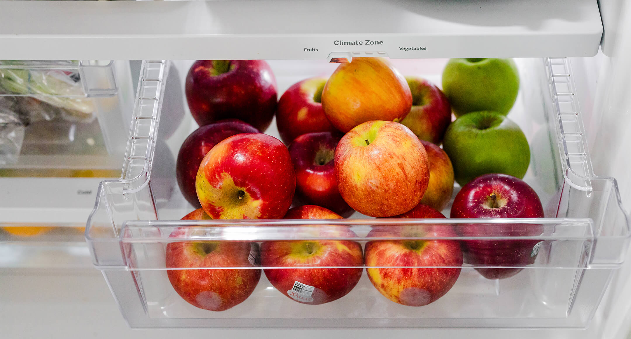Fresh red and green apples in a refrigerator crisper.