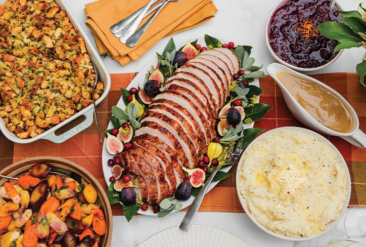 A holiday table set with roasted turkey and traditional sides.