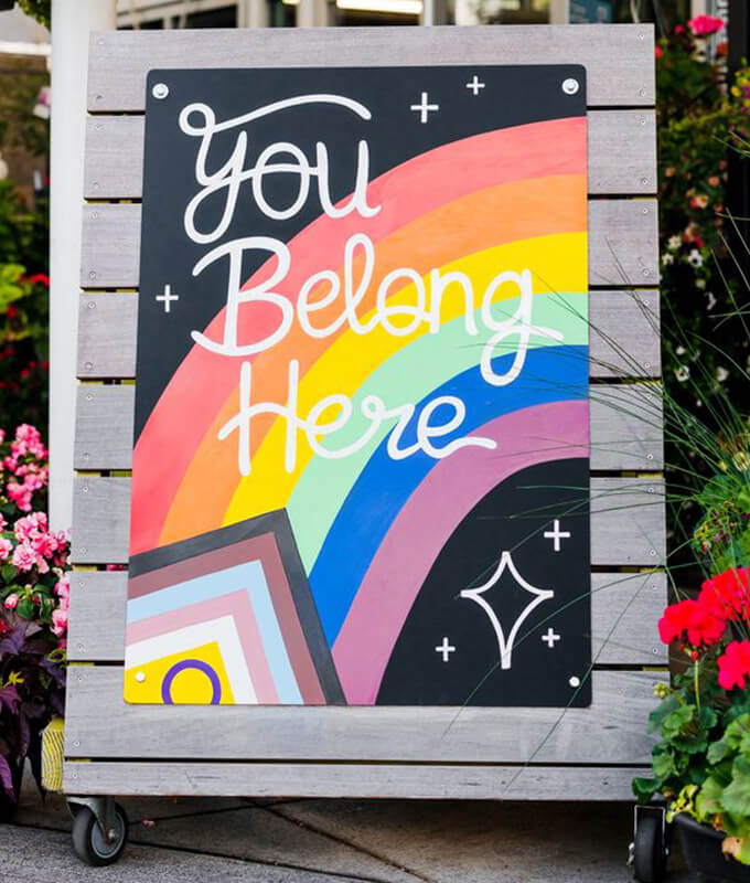 a chalk illustration on a easel board with a rainbow and the words "You Belong Here"