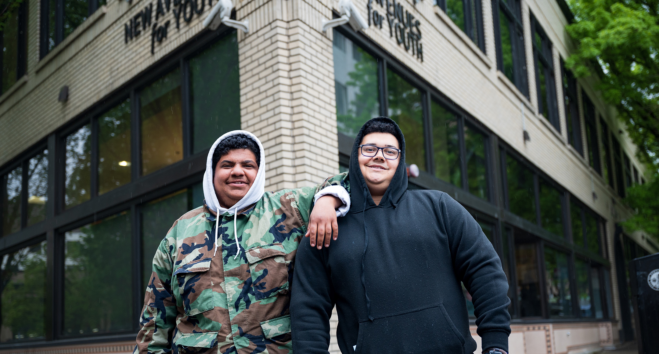 Two individuals standing outside of the New Avenues for Youth building. 