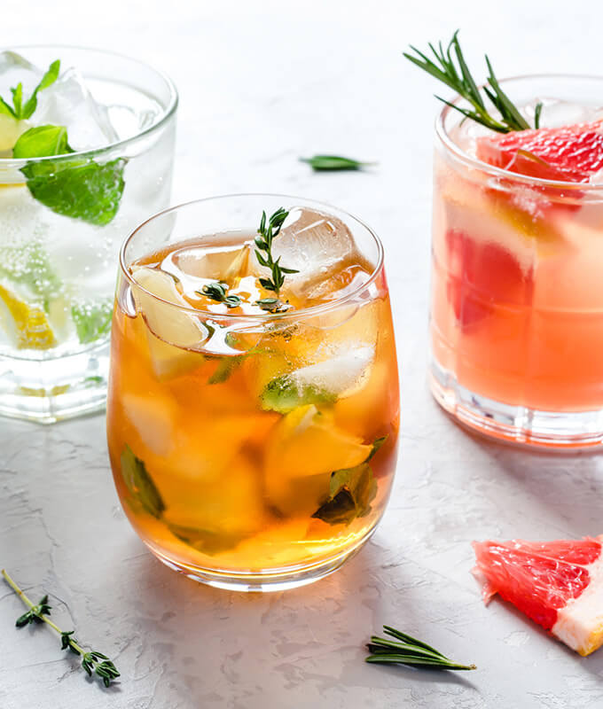 three beverages on a counter with ice in various colors representing different seasonal drink recipes
