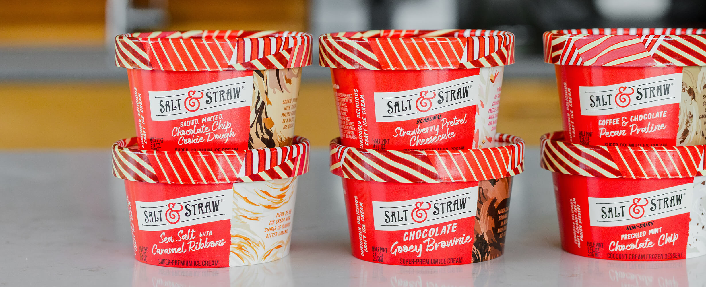 An image of Salt & Straw ice cream half pints on a counter. Flavors include Chocolate Chip, Pecan Praline, Strawberry Pretzel Cheesecake, and Sea Salt with Caramel Ribbons.