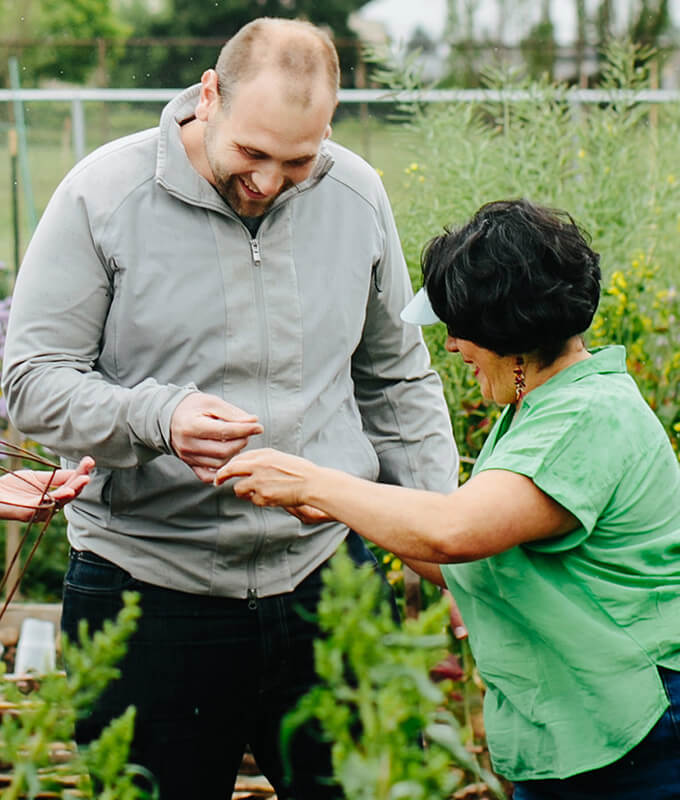 two smiling people in a garden looking at something in their hands