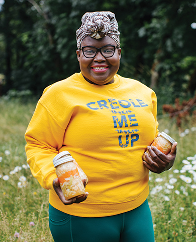 Elsy Dinvil of Creole Me Up holding 3 jars of Pickleez