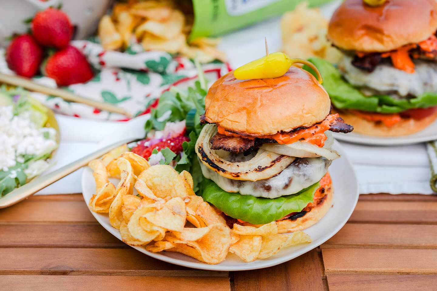 A burger on a plate with a side of potato chips.