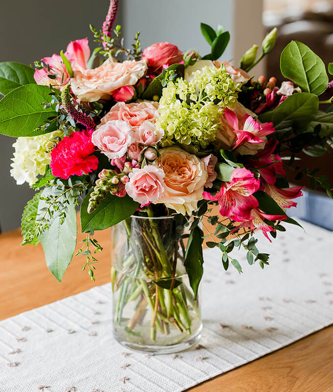 a beautiful fresh bouquet of flowers in a clear vase with water on a table