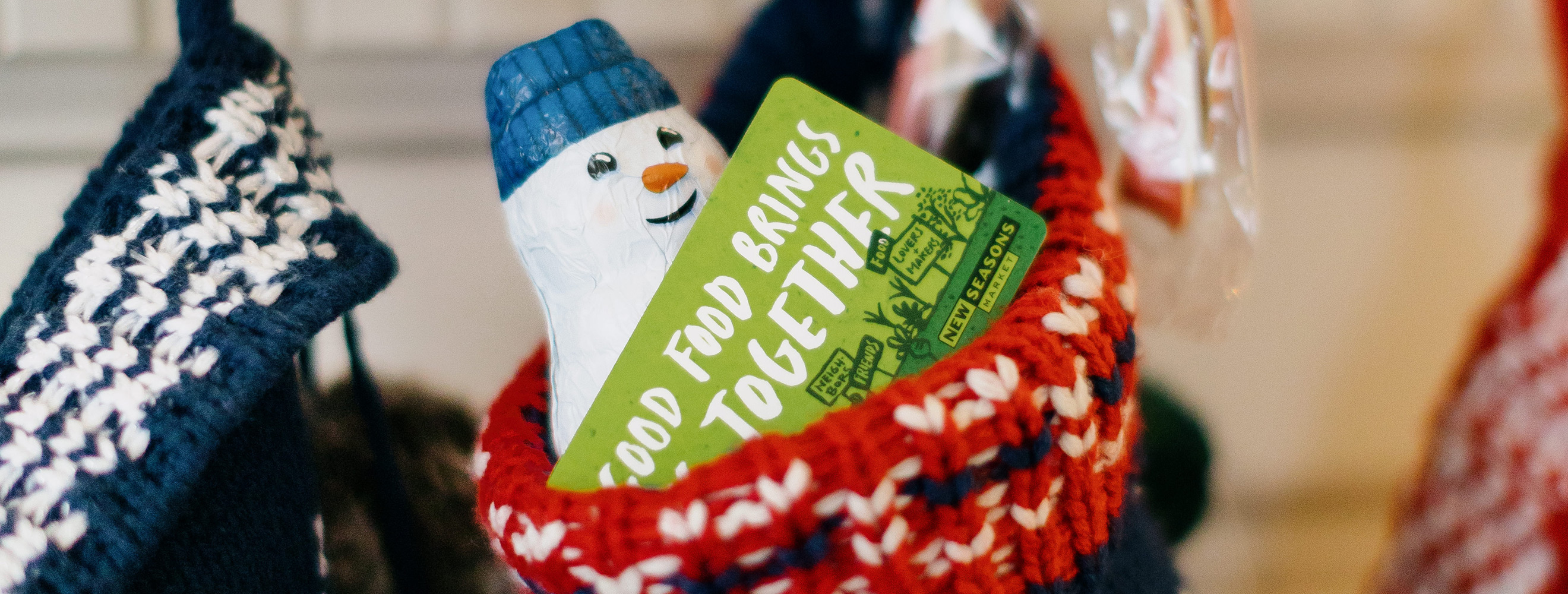 Gift cards and other toys in a stocking hanging from a fireplace mantle.