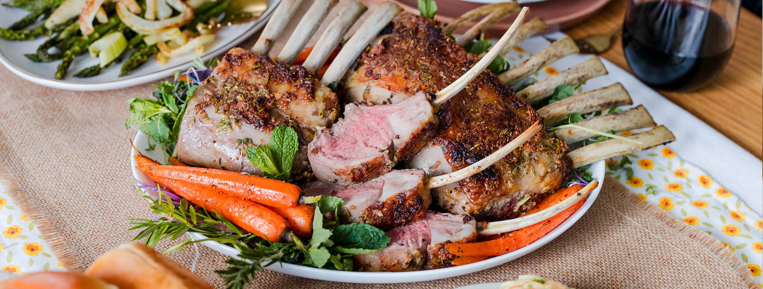 a platter with lamb and carrots, on a festive spring table with other sides.