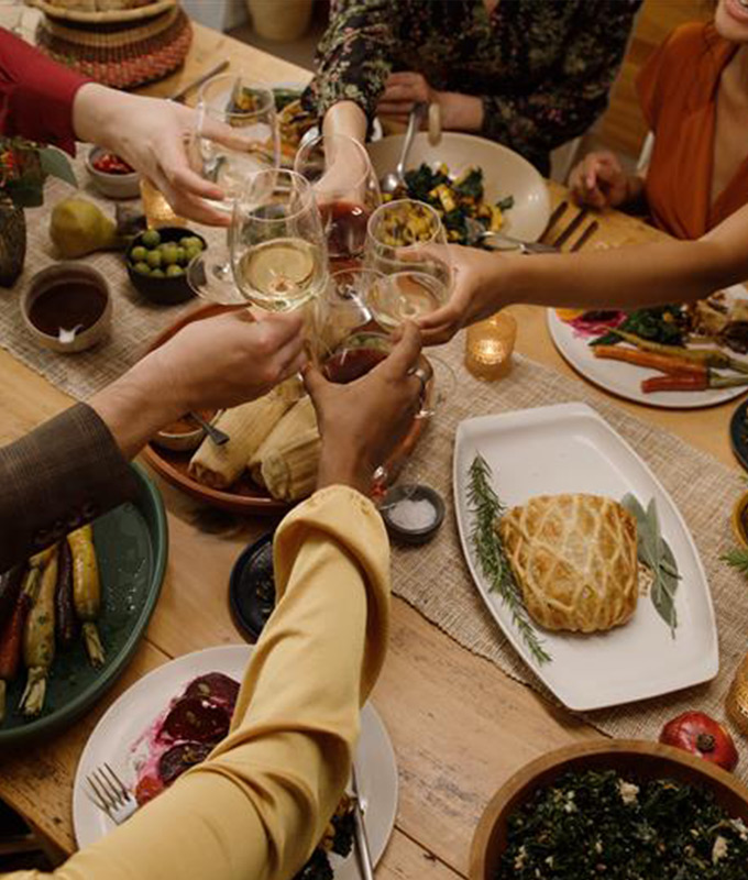 A group of people holding wine glasses to cheers over a holiday table.
