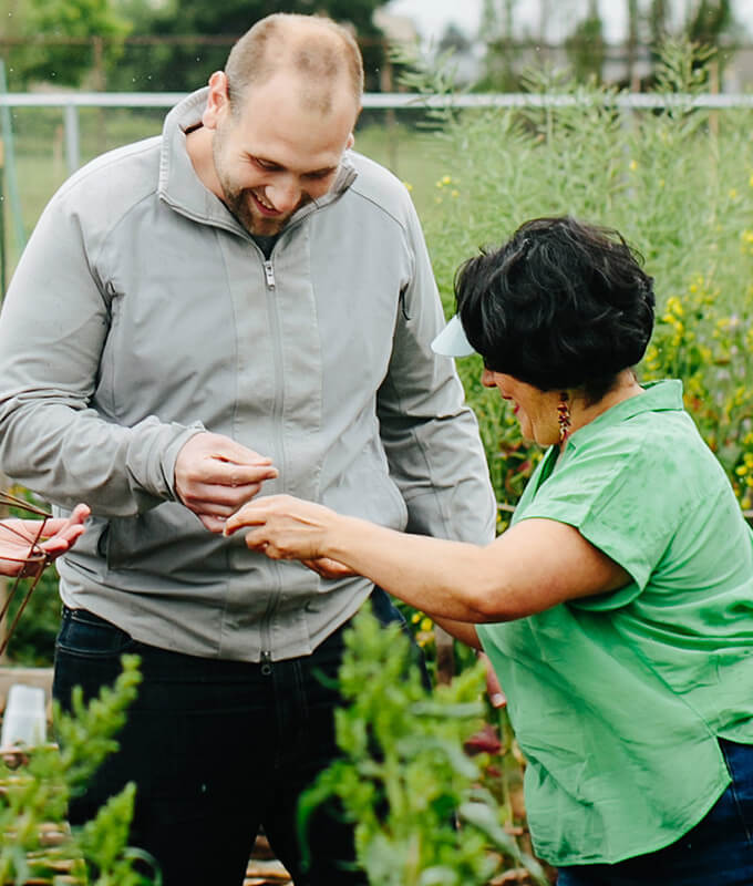 two people in a garden looking at something in their hands.