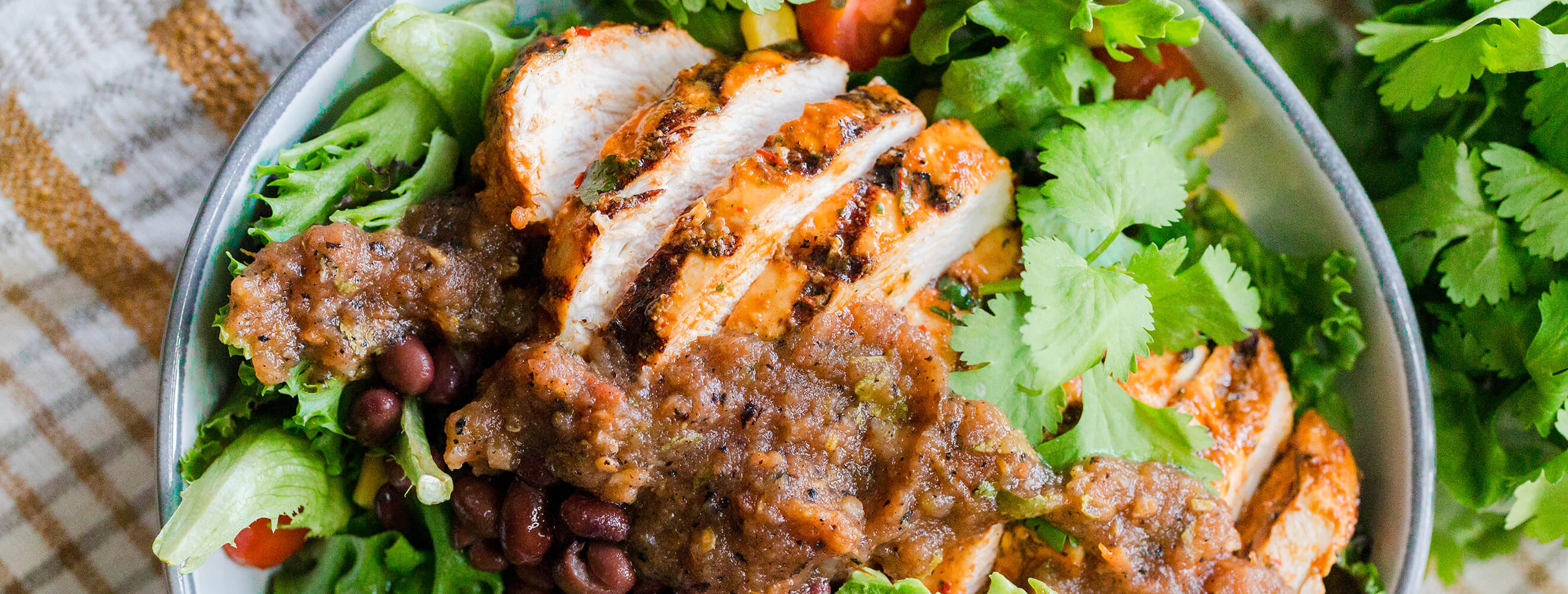sliced roasted chicken on a plate with beans and rice and herbs